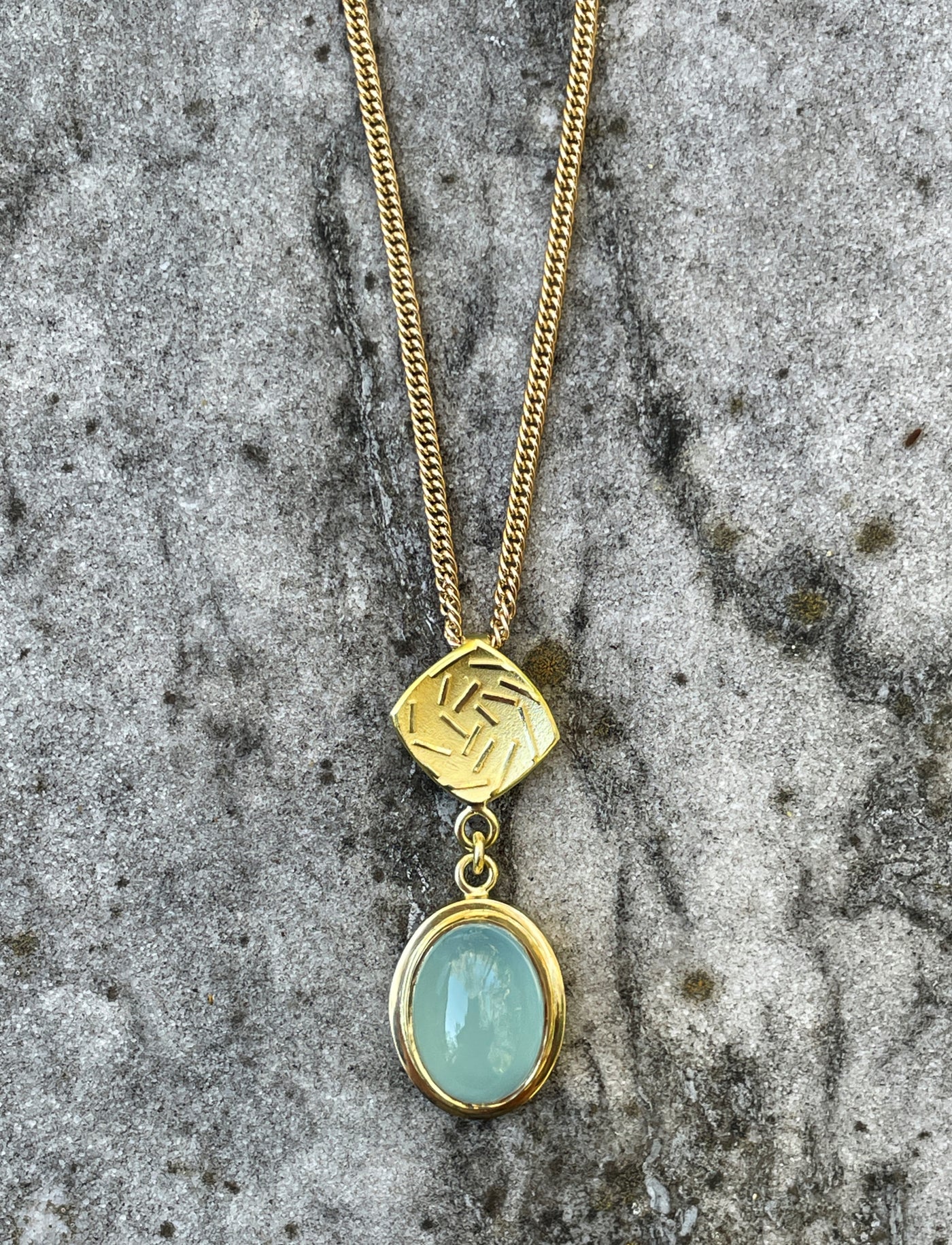 18ct gold Spiral Galaxy pendant featuring an oval pale blue aquamarine gemstone and sculptural spiral detailing, suspended from a gold chain.