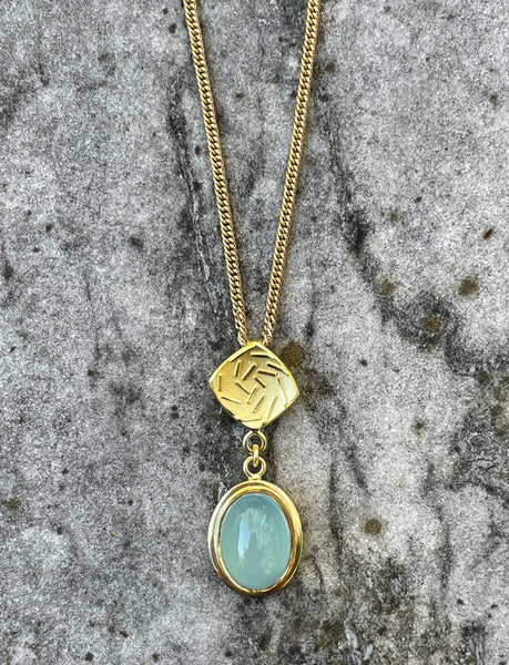 18ct gold Spiral Galaxy pendant featuring an oval pale blue aquamarine gemstone and sculptural spiral detailing, suspended from a gold chain.